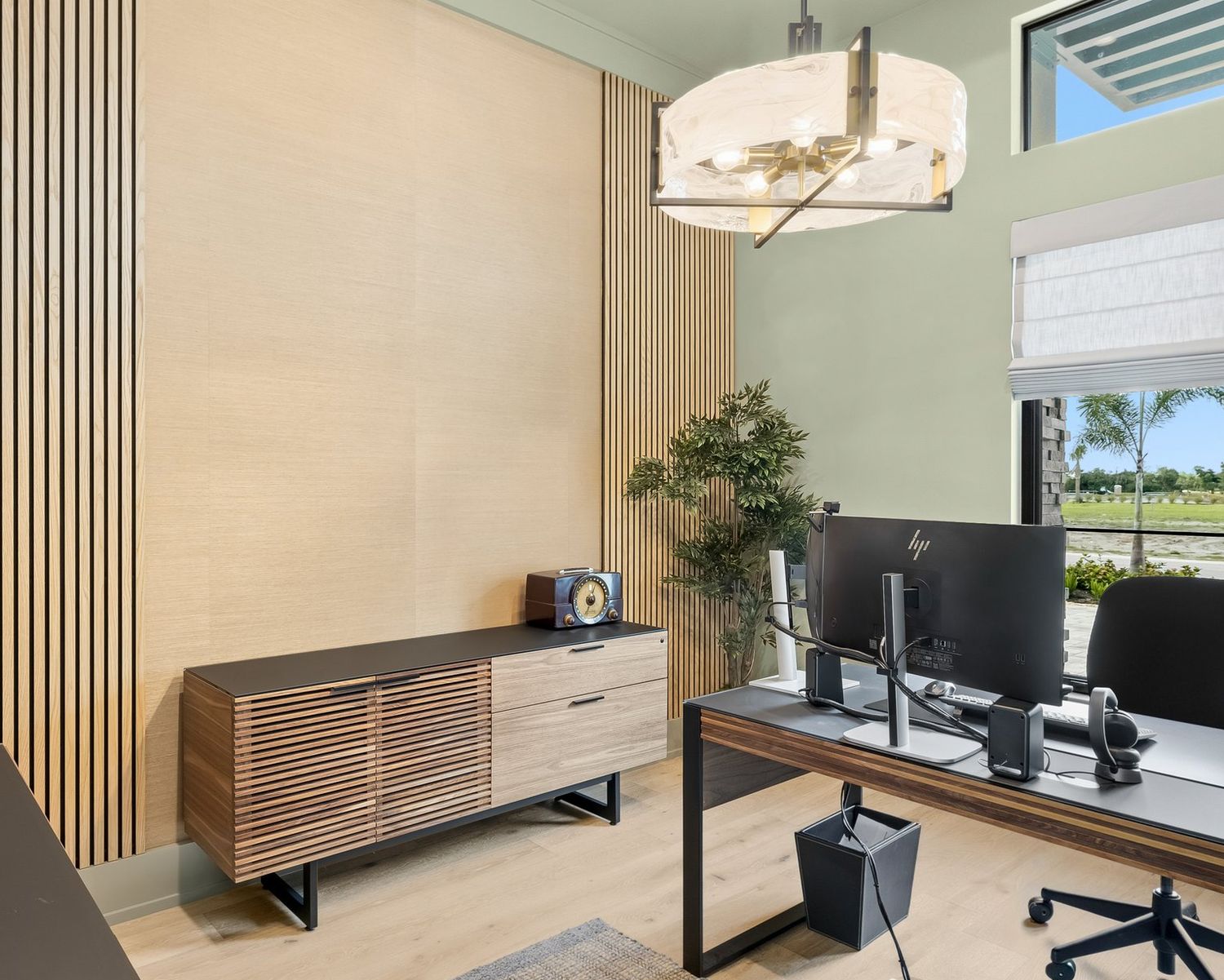 Home office with natural wood slats and a grasscloth inset wall behind a walnut credenza and desk